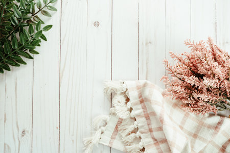 Pretty pink and green themed flatlay, top down view, with pink dried flowers, green leaves and a plaid towel, on white wood backgroundの写真素材