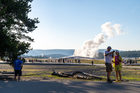 Wyoming, USA - July 19, 2022: Tourists walk towards Old Faithful Geyesr in Yellowstone National Park, waiting for its eruptionのeditorial素材
