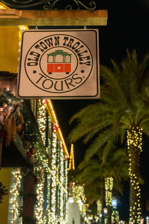 St. Augustine, Florida - December 30, 2022: Sign for the Old Town Trolley Tours booth, during the Nights of Lights. Christmas lights bokeh in backgroundのeditorial素材