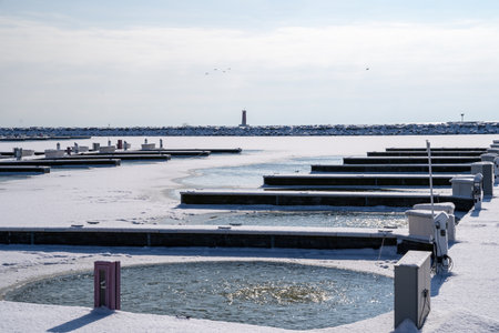 View of the docks and boat slips on Lake Michigan, with the Sheboygan Lighthouse in the distance, taken in winter in Wisconsinの写真素材