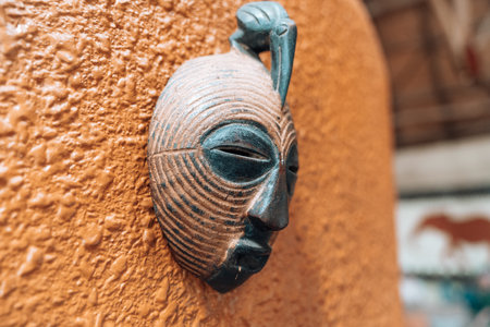 Side view of African mask on a orange stucco wall hanging for decoration. Shallow depth of fieldの写真素材
