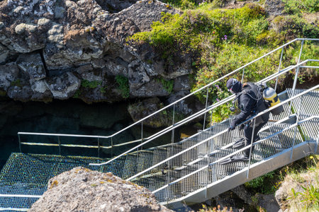 Thingvellir National Park, Iceland - July 9, 2023: Tourist scuba diver prepares to divel between the two tectonic plates at the steps to enter the cold water at Silfraのeditorial素材