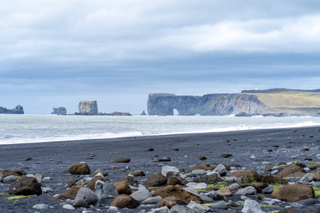 Black sand beach looking toward sea stacks and arches, in Vik, Iceland, Dyrholaeyの写真素材