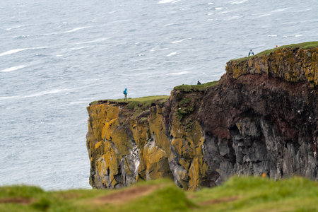 Tourists climb and walk on top of the cliffs at LÃ¡trabjarg, the westernmost point of Iceand and Europe is also a famous bird colonyの写真素材