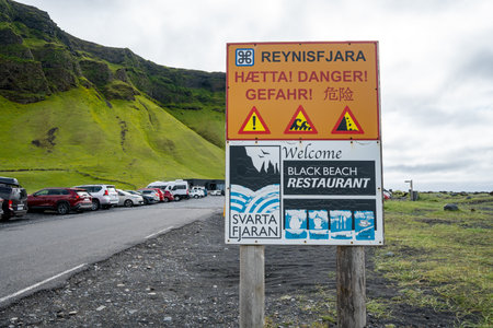 Vik, Iceland - July 8, 2023: Sign reminding tourists and visitors of the dangers of sneaker waves at Reynisfjara Black Sand Beach.のeditorial素材