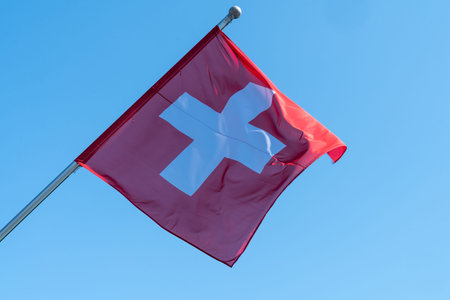 Swiss Flag blowing in the wind against a blue sky. Geneva, Switzerland