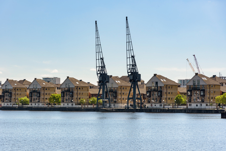 Port cranes and houses at Royal Victoria Dock in London, UKの写真素材