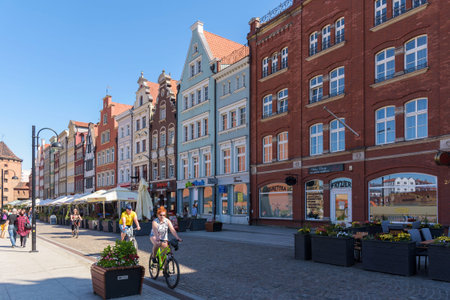 Gdansk, Poland - June 14, 2020: People ride bike picturesque Stagiewna street in city downtown