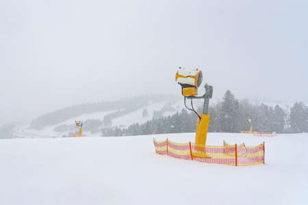 Modern snow cannon on a ski slope at snowstormの写真素材