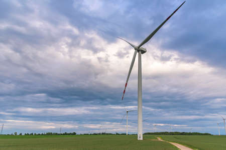 Wind turbines on a wind farm against cloudy sky at sunsetの写真素材