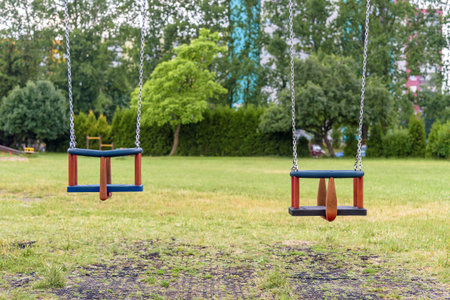 Two empty swings with chains on the playgroundの写真素材