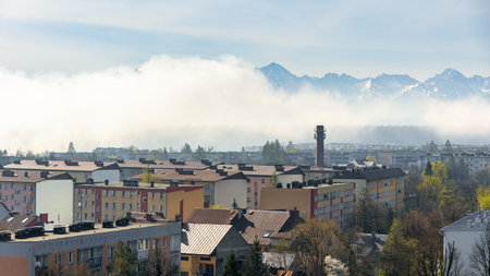 Panoramic view of the rooftops of Nowy Targ with snow capped Tatra mountains revealing from the...