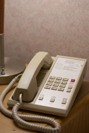 A hotel phone sitting on a bedside tableの写真素材