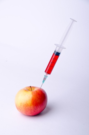 syringe with red liquid into red appleの写真素材