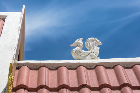 On the roof of thailand temple in the afternoon with lai thai bird statue with blue sky backgroundの写真素材