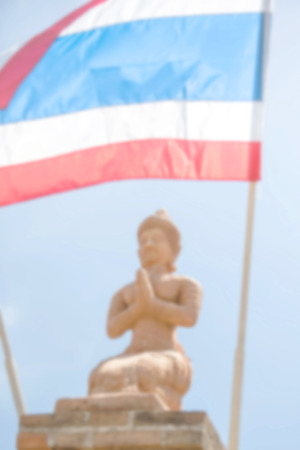 Defocus of thai angel statue with thai flag and clear blue sky background in public location temple in lampoon thailandの写真素材
