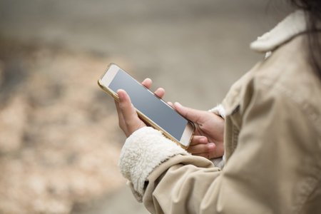 Asian young girl child playing mobile smart phone in winter suit, closeup shot.