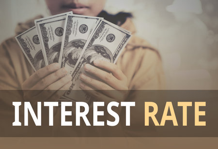 Interest Rate word over young girl holding dollar bills.