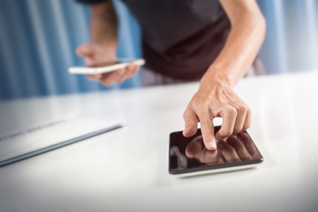 Business man using tablet while analyzing documents in the office workplace.