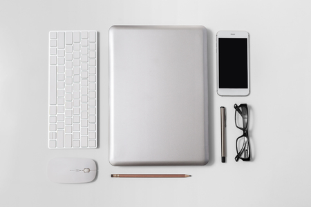 Working table with business object flat lay display laptop, keyboard, mouse, smartphone, pen, glasses, pencil top view on the modern desk.の写真素材