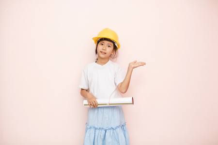 Smile little girl as architect engineer dream to future shows hand welcome.の写真素材