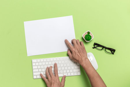 Hand point to paper office desk with keyboard mouse from above view.の写真素材