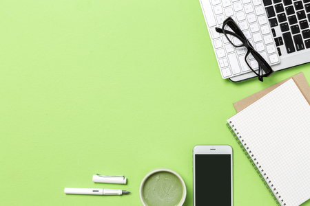 Mock up of business workplace on green background of desk table, top view photography in studio.の写真素材