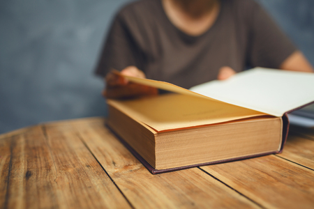 Senior woman reading a book at living room with old vintage table and concrete wall background.の写真素材