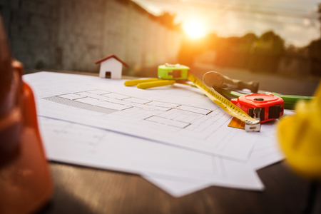 Engineer desk closeup, helmet, house plan with equipment and sunflare effect.の写真素材