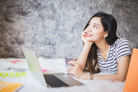 Young women are shopping online with laptops while sitting in the living room.の写真素材