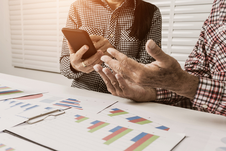 An elderly business woman is using a telephone. Explain financial information. To the male businessman. Chief of Officeの写真素材