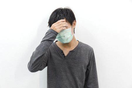 Men with migraine headache fever and dust mask wearing grey shirt long sleeve.の写真素材