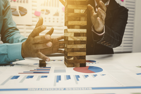 Investment Risk Management, Business man and woman stop wood tower building for tumbledown.の写真素材