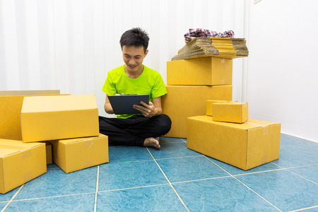 Young man as SME start up own business with box, work at home product delivery and checking order of customer of small business entrepreneur.の写真素材