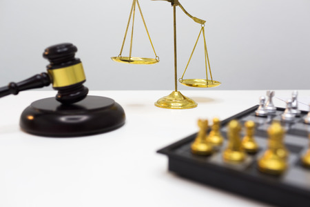 Dark wood gavel and golden scales put on white table in lawyer office.の写真素材