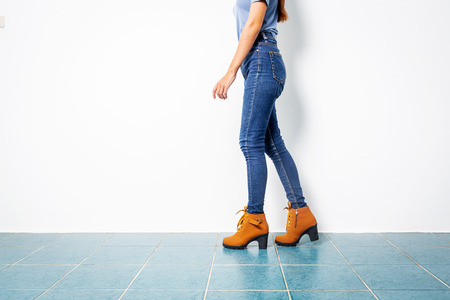 Young Asian 20s girl with jeans sexy leg with brown shoes fashion on white wall background.の写真素材