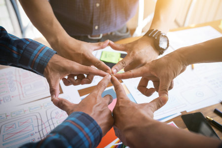 UX/UI Designers joining hands to motivate collaboration after successfully completed the target set.