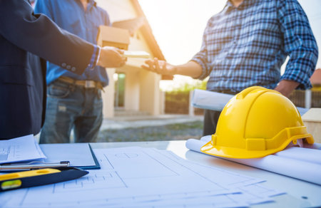 Real estate agent giving house keys in front of house stand with architect engineer after build...