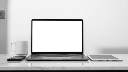 Mock up stylish workspace with empty laptop screen white blank and coffee cup, tablet and mobile smart phone, black and white color tone.の写真素材