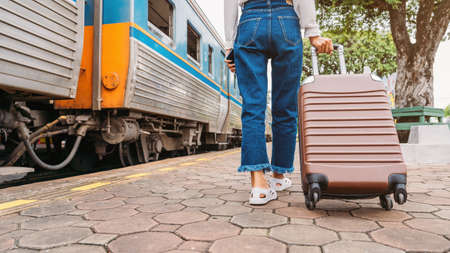 Traveler tourist woman walking and dragging luggage bag at train station and searching hotel for booking room.の写真素材