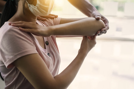 Physical therapist works to examine the treatment of patient's injured arm.