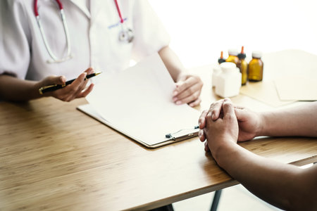 Female doctor taking a patient history, close up at hands of patient.