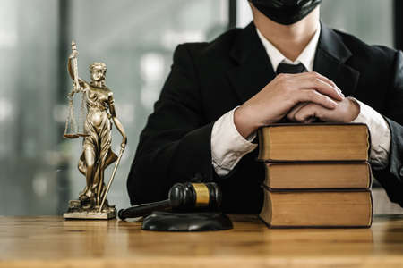 Lawyer sitting at desk, close up at statue, legislation and justice concept.の写真素材