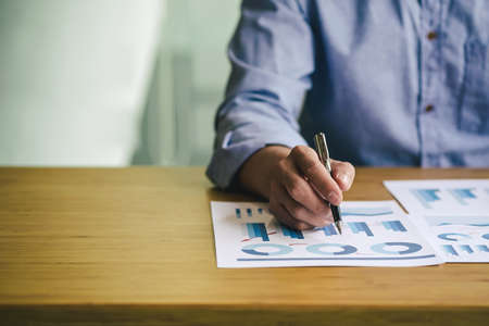 Business man pointing on data paper, close up hands holding pen.の写真素材
