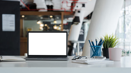 Mockup laptop computer with white screen put on desk table of business office.