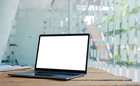 Laptop with blank white screen on wooden table for montage your ads.の写真素材