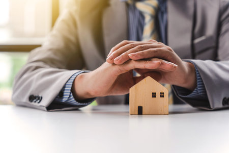 Business man hands with house model, real estate insurance concept. Mortgage and payment of taxes.