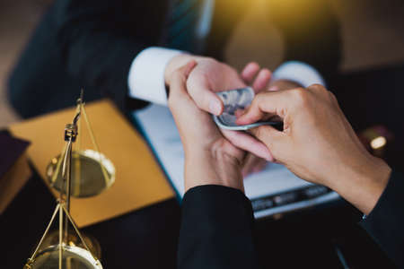 lawyer taking dollar bribe from the female client for falsifying documents, businessman taking bribes corruption illegal fraud bribery concept.の写真素材