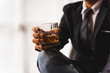 Businessman wearing suit sits in the luxury bar in gentlemen club and drink whiskey.