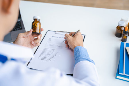 Close-up of doctor's hands writing prescription and holding bottle with pills. Healthcare, medical and pharmacy concept.の写真素材